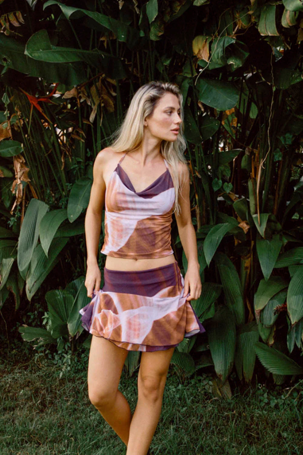 Woman wearing a patterned dress standing in front of green foliage