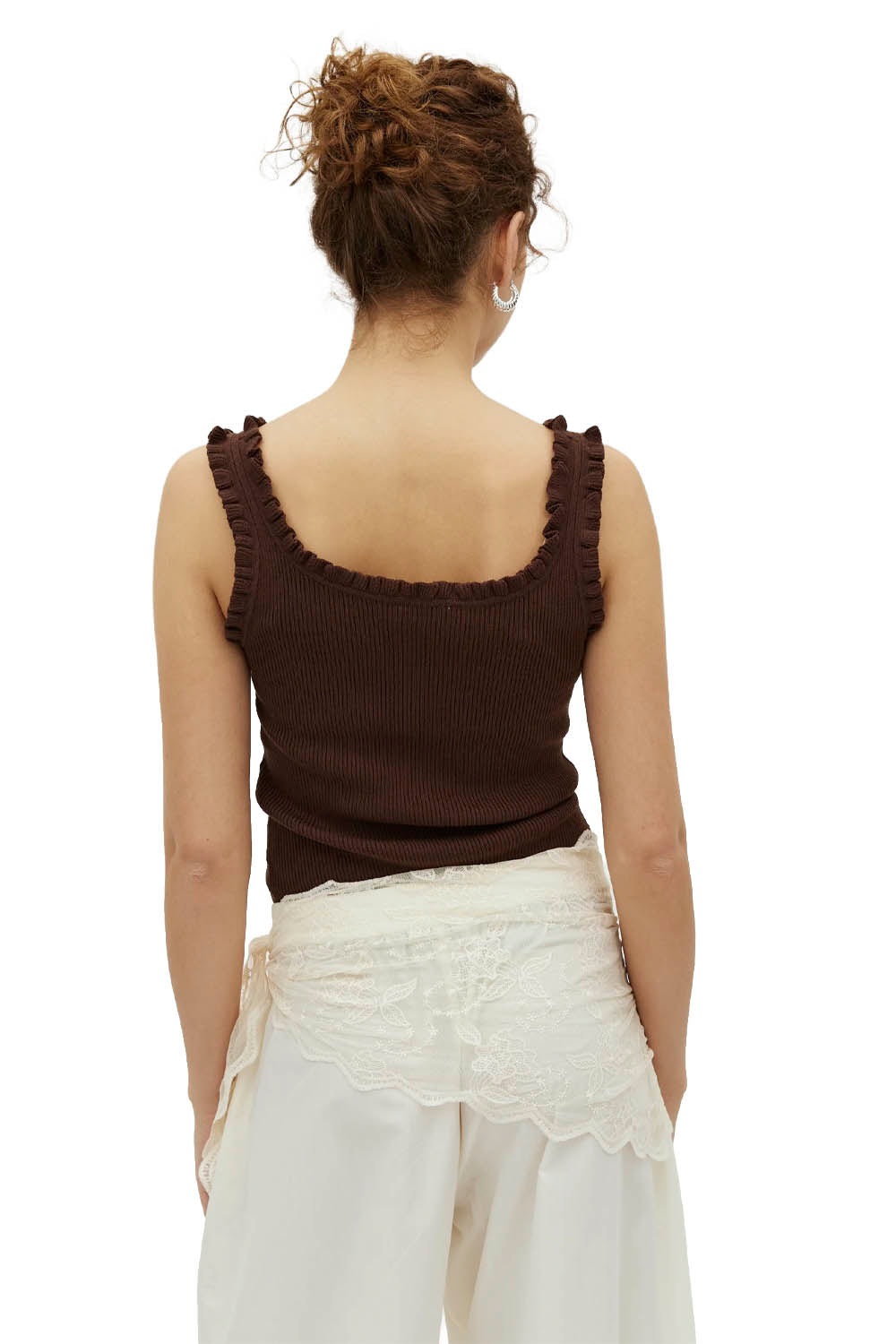Woman wearing a brown tank top and white pants on a white background