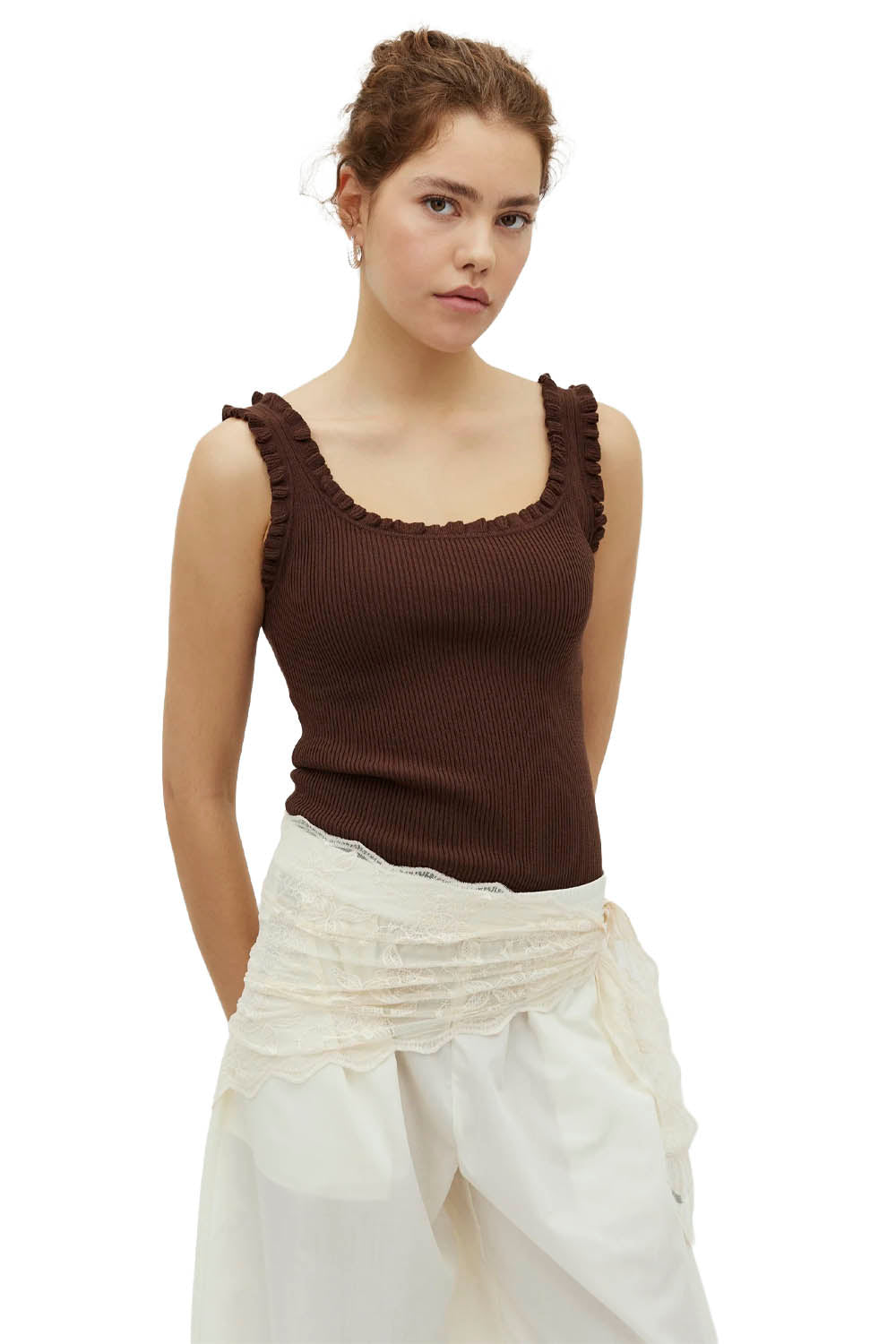 Woman wearing a brown tank top and white pants on a white background