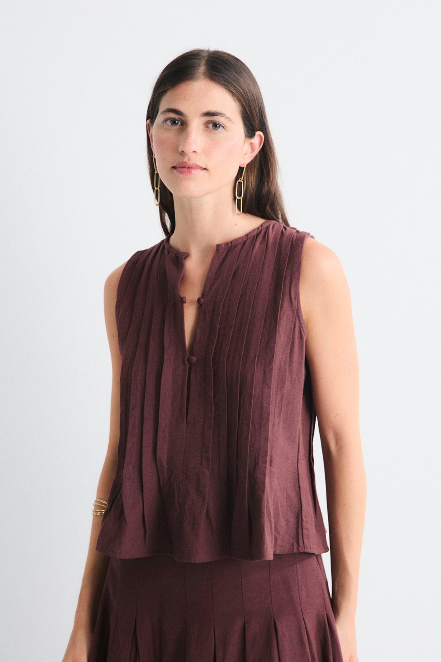 Woman wearing a sleeveless brown top against a white background