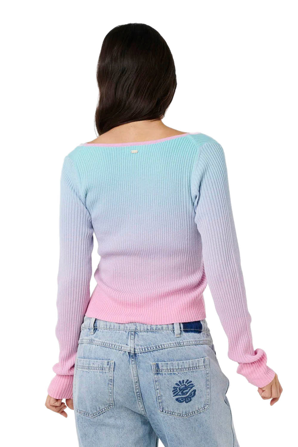 Woman wearing a light blue and pink gradient sweater with jeans on a white background