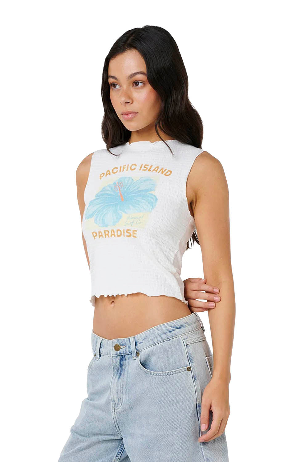 Woman wearing a white sleeveless crop top with graphic design and light blue jeans on a white background