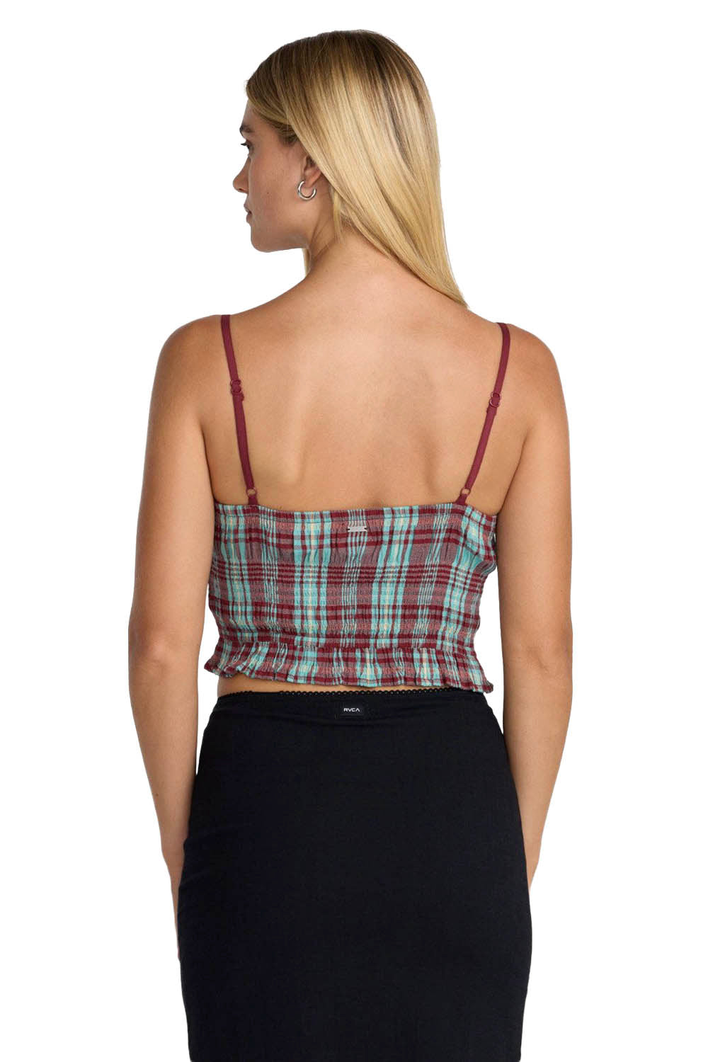 Woman wearing a plaid top and black pants on a white background