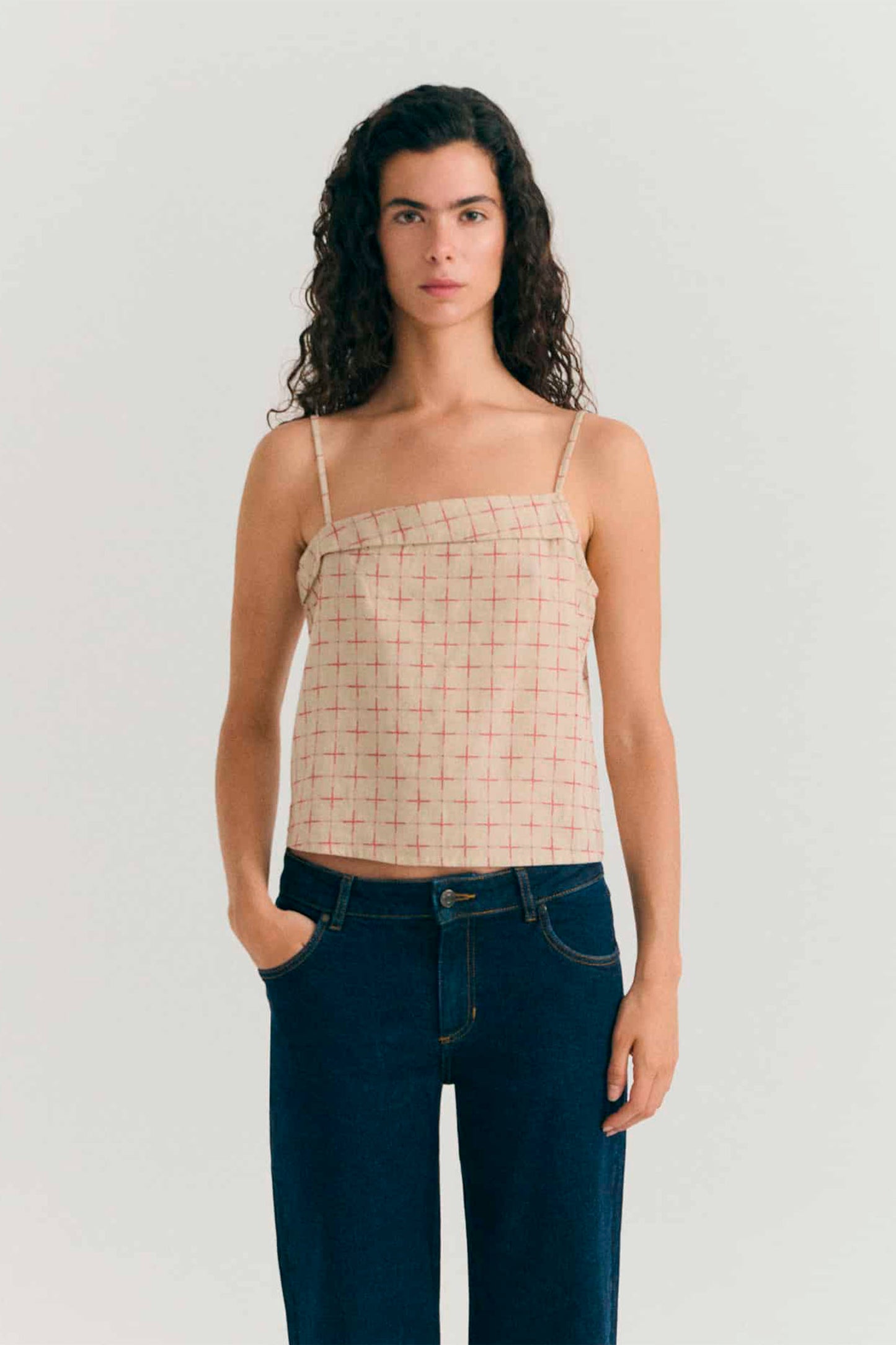 Woman wearing Red checkered Thinking Mu Raida top with thin straps on a white background