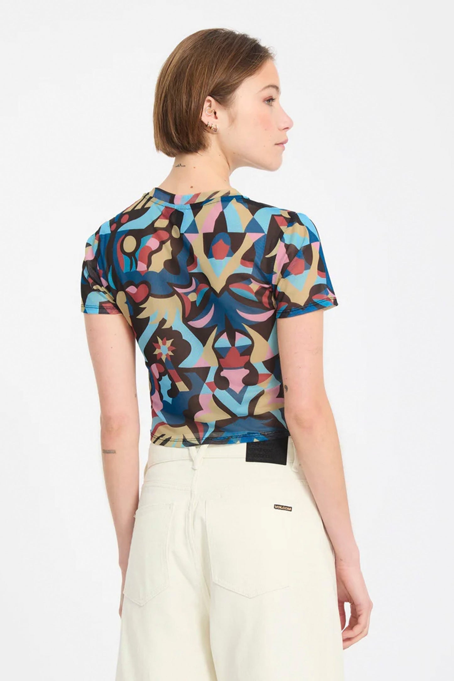 Woman wearing a colorful Volcom Fa Bruno Lukas crop top on a white background