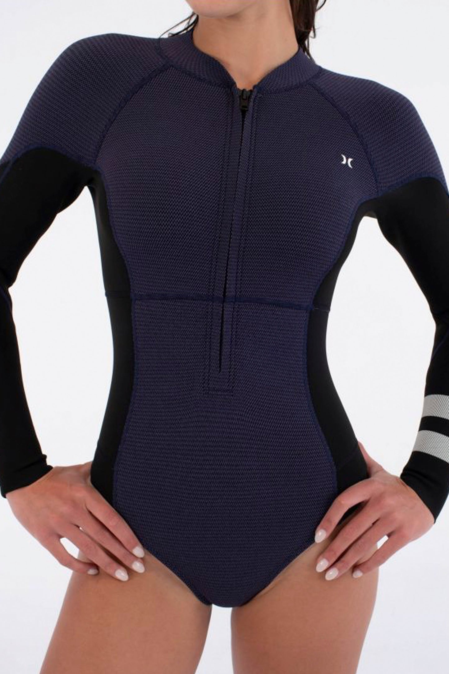 Woman wearing a navy blue and black long-sleeve Hurley springsuit with a logo on a white background