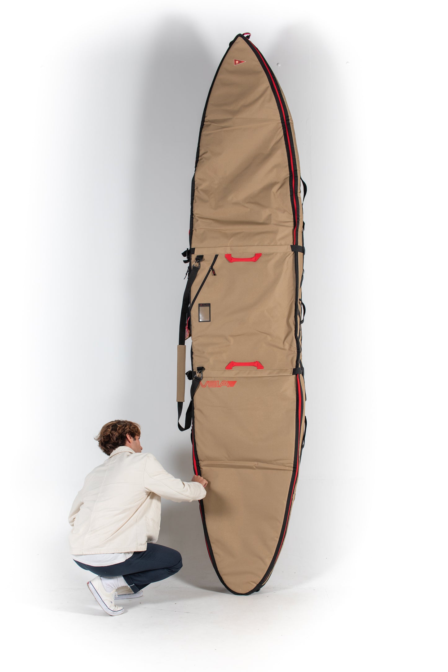 Pukas Surf Shop Veia Supplies Person holding a large beige surfboard bag against a white background