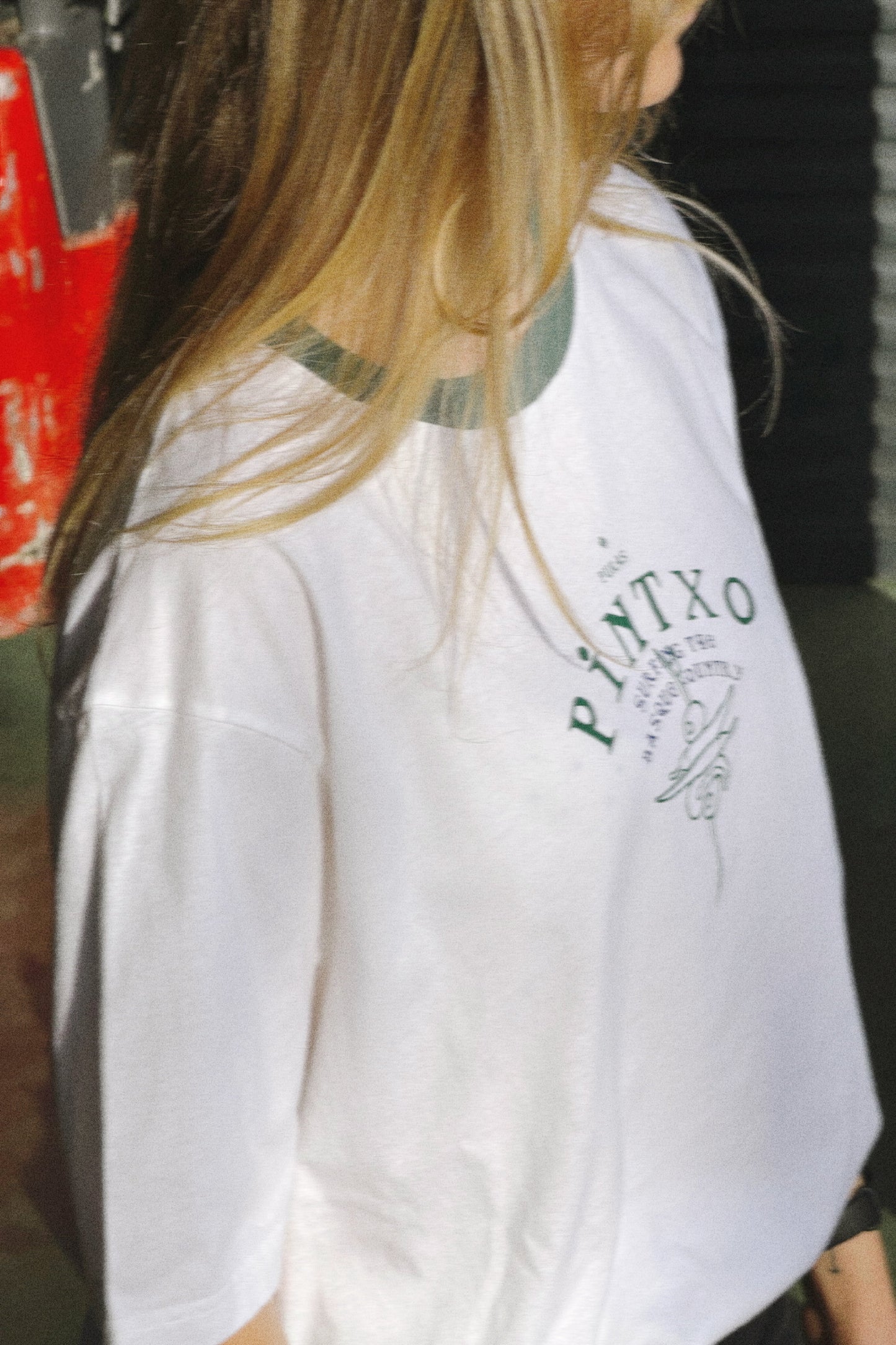 Person wearing a white shirt with 'PINTXO' text and logo.